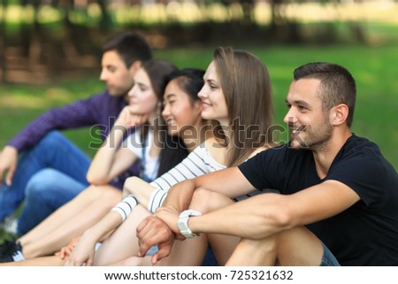 Adult attractive friends having fun on open air. Focus on handsome man smiling and looking at camera. Cheerful friends company spending free time outdoors