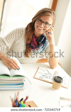 Young woman sitting at a desk among books. Student