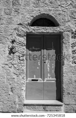 Outdoor relief of Virgin Saint Mary, Madonna with Child, near the door.  Entrance to a old house on the island of Malta. Black and white picture