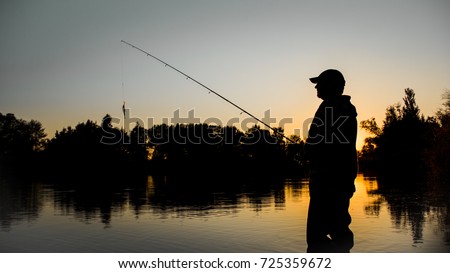 Fishing. spinning at sunset. Silhouette of a fisherman Royalty-Free Stock Photo #725359672