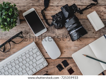 top view of photographer work station, work space concept with digital camera, notebook, memory card, smartphone on wooden table Royalty-Free Stock Photo #725359933
