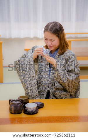 Women in traditional yukata dress are drinkiing Japanese green tea in Japanese style room 
