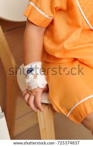 Saline intravenous (iv) drip on children hand in hospital.