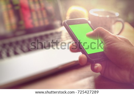 Stock exchange concept, hand holding mobile and note in lab top. Selective focus and toned image, free space for text.