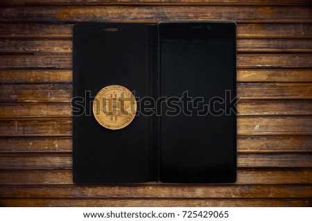 Gold bitcoin cryptocurrency with a smartphone on a wooden table. Electronic money mining concept. copy space