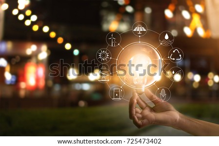 Hand holding light bulb in front of global show the world's consumption with icons energy sources for renewable, sustainable development. Ecology concept. Elements of this image furnished by NASA.  Royalty-Free Stock Photo #725473402