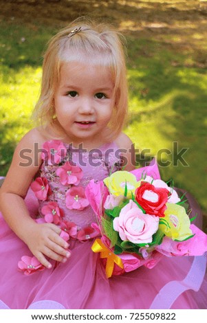 Beautiful little girl blonde with a candy bouquet at a children's party outdoors