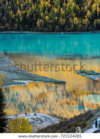 Reflection of river and autumn forest with two peoples stand at bottom in Kanas lake, Xinjiang, China
