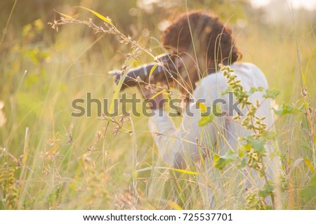 Blurred photo of Professional photographer are shooting in a meadow during sunset.