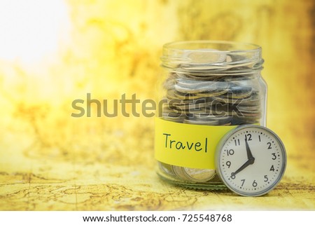 Time, Travel and Saving Concept. Full of coins in clear bottle with yellow label note with Travel word and vintage round watch on world map.