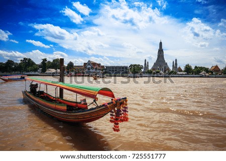 Long tail tour boat in front of Wat Arun in Chao Phraya river. Wat Arun is a Buddhist temple in Bangkok Yai district of Bangkok, Thailand. Wat Arun is among the best known of Thailand's landmarks