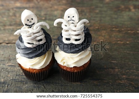 Halloween cupcakes with skeletons on wooden table