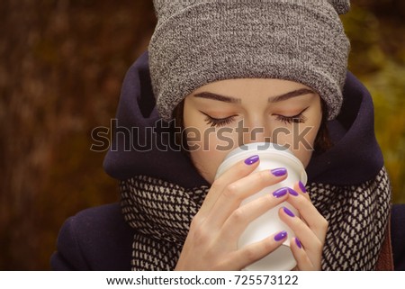 young woman drinking hot coffee in the dark autumn park