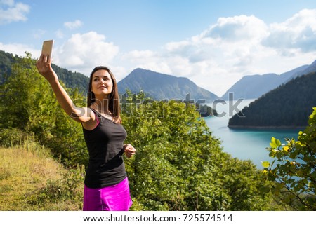 Young woman taking pictures on the phone in the mountains
