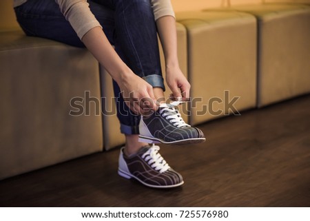 Cropped image of young woman lacing up bowling shoes ready to play bowling