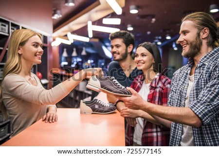 Cheerful young people are taking bowling shoes and smiling ready to play bowling