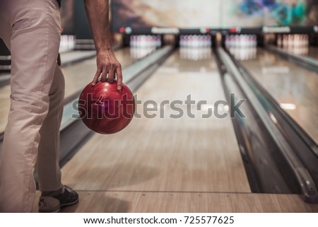 Cropped image of man holding a red bowling ball ready to throw it