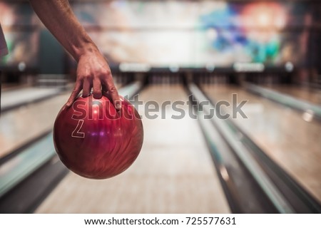 Man's hand holding a red bowling ball ready to throw it Royalty-Free Stock Photo #725577631