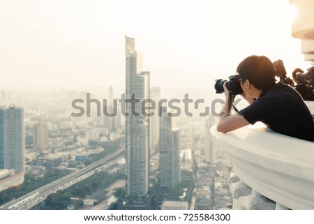 Young man taking a photo using dslr camera to view of Bangkok, Beautiful view of the cityscape.