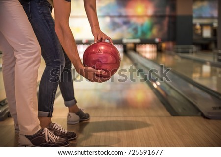 Cropped image of beautiful girl and handsome guy holding a bowling ball while playing