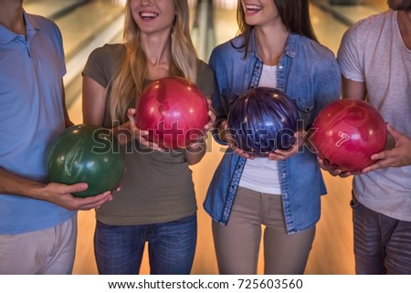 Cropped image of happy young friends holding balls and smiling while playing bowling together