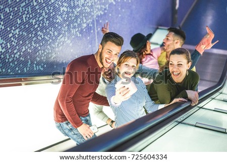 Happy friends taking a photo selfie with instant camera on escalator in metro underground - Group of young people having funny moment taking pictures for social media - Friendship, fun, social concept