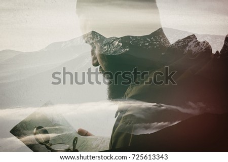 Photo of stylish bearded traveler with a compass and map in hand. Double exposure, beautiful mountain landscape background. Made in vintage style.