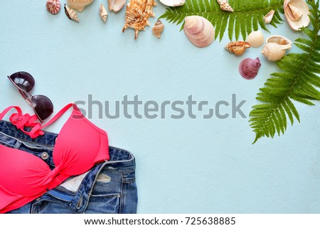 Female summer bikini swimsuit and accessories collage on blue with palm branches, hat and sunglasses. flat lay, top view