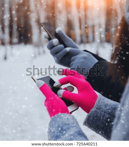 Couple using smartphone in winter with gloves for touch screens. Backgound