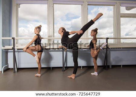 Ballet class, coach teaches two girls ballerinas to perform exercises