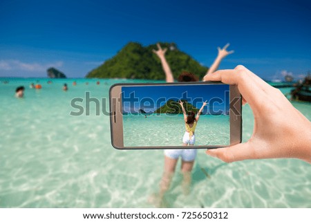 hand holding smartphone with take a photo  on summer beach