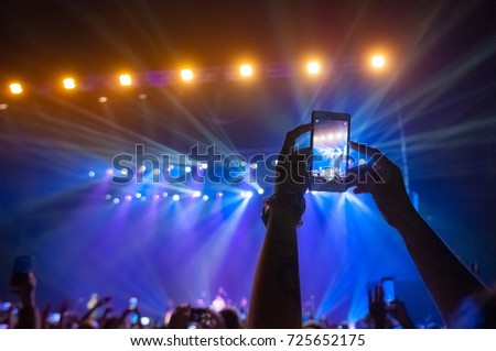People in the crowd at a concert make video recordings and pics on a smartphone of published in social networks  