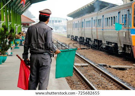 Train Station Master is Waving Green Flag To Make The Train pass at Platform of Railway Station,cinematic photography film grain tone style