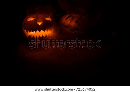 Halloween - old jack-o-lantern on black foggy background. Closeup of scary halloween pumpkins