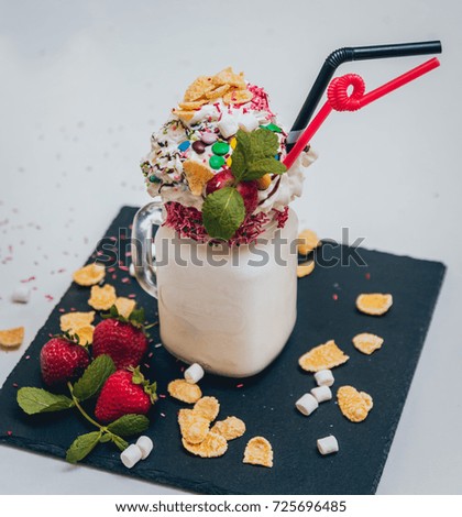 Glass of strawberry milkshake with whipped cream and fresh strawberries