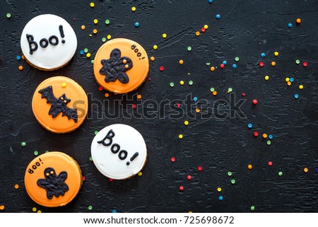 Halloween gingerbread cookies with pictures of bat, ghost on black background top view copyspace