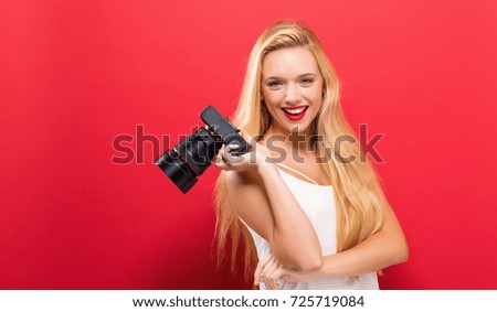 Young woman comparing professional camera on a solid background