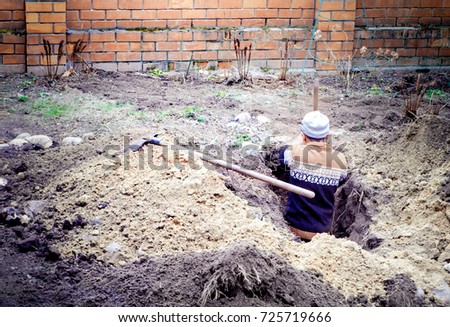 one people Builder worker digs a pit for two pits in the yard of a private house
