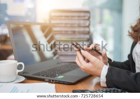 Business woman at working with financial reports and using mobile smartphone in the office
