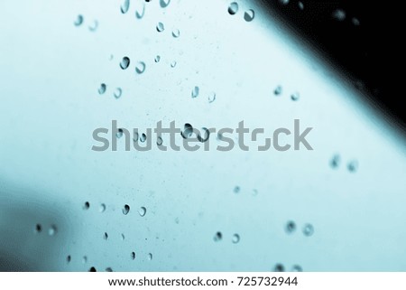 Water droplets caused by rain falling into the car glass.