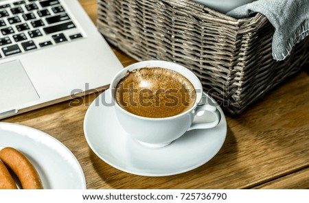 Working table with a cup of coffee, laptop computer, Wicker baskets.