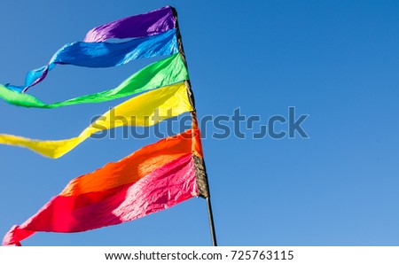 Colorful rainbow triangle flag shows up against the blue sky.