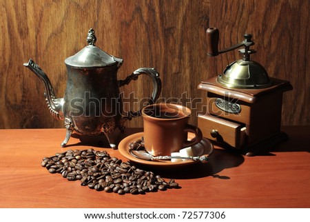 Cup of coffee, coffee pot and grinder over wooden background