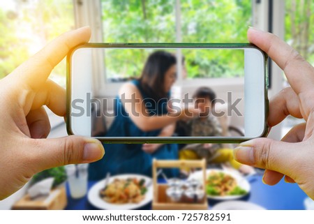 Take a photo with smartphone on Portrait asian boy and his mother in the restaurant background - Mother 's day concept