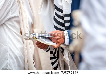 Hands and prayer book close-up. Orthodox hassidic Jews pray in a holiday robe and tallith Royalty-Free Stock Photo #725789149