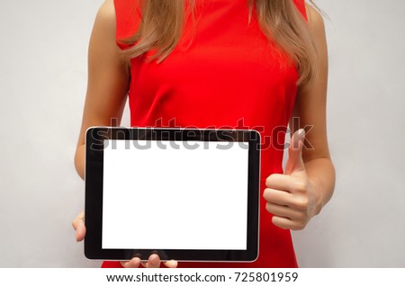 Young woman in red dress holding in hands tablet computer with blank screen and showing thumbs up gesture. Product presentation. Special offer. Best offer.