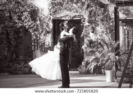 asian newly wed bride and groom celebrating marriage outside a building, black and white.