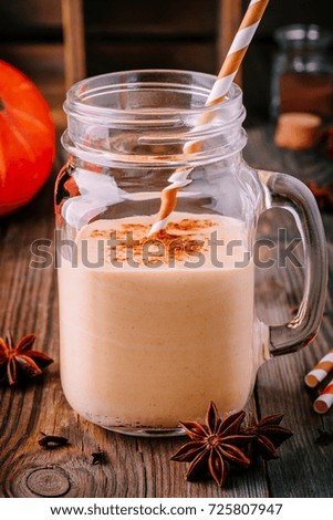 Pumpkin pie smoothie with cinnamon in mason jar on wooden rustic background