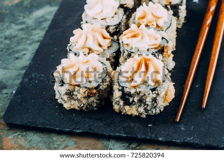 Hot fried Sushi Roll with Cheese Philadelphia on dark stone slate board on concrete table background. Japanese food.