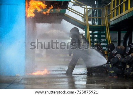 Firemen using water from hose for fire fighting at firefight training of insurance group. Firefighter wearing a fire suit for safety under the danger case.Firefighters training,